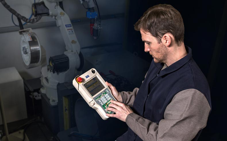 a person programming a remote for a robot welder